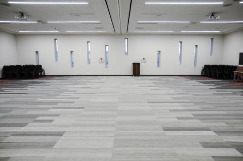 Large square carpeted room with tall narrow windows on one side